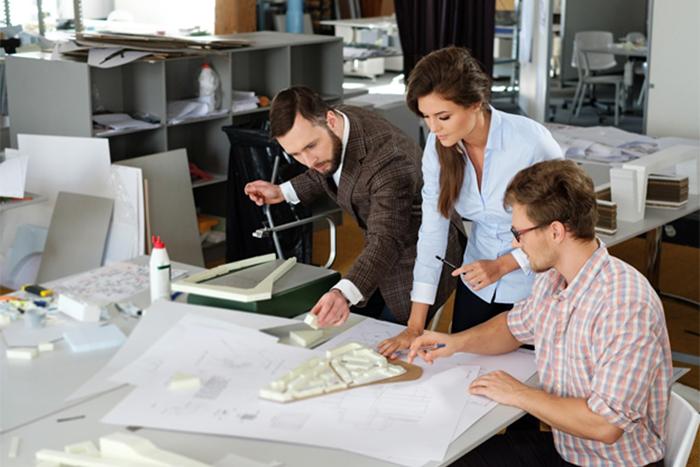 three people standing around a table with a blueprint