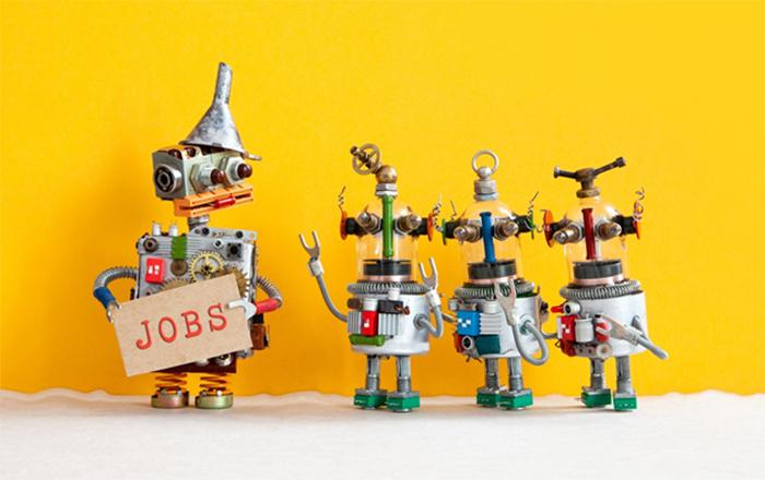 four robots, one holding a sign that reads jobs
