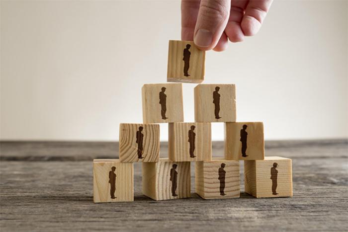 hand stacking building blocks into a pyramid