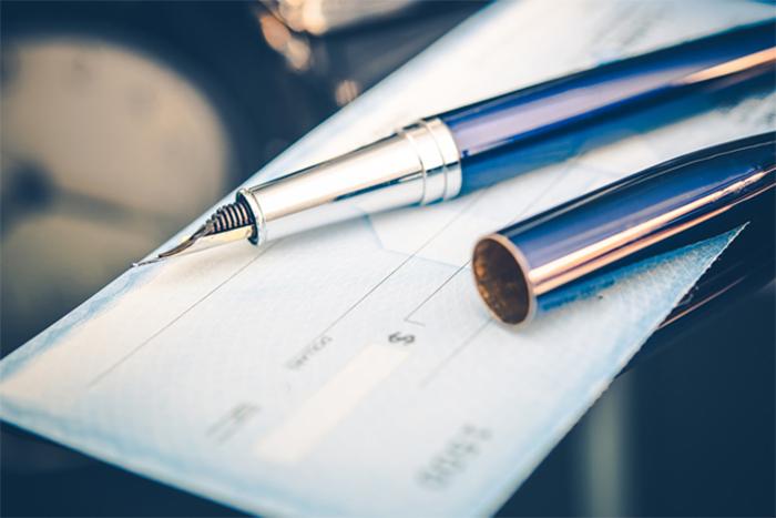 close up of a pen on top of a checkbook